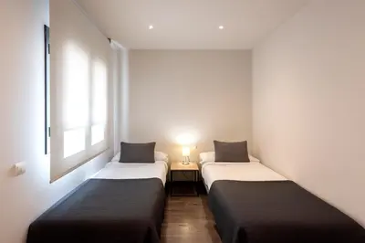 two beds in a small room with a lamp at Espais Blaus Apartments in Barcelona