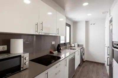 a kitchen with white cabinets and a black and white appliances at Espais Blaus Apartments in Barcelona