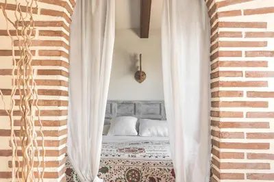 a bedroom with white curtains and a bed with a rug at Can Caponet in Lliçà d'Amunt