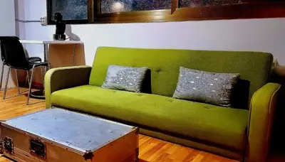 a green couch with two pillows and a trunk at Great Sleep Loft in Barcelona