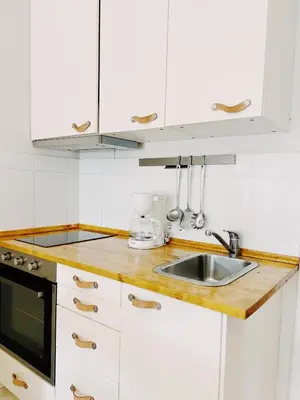a kitchen with white cabinets and a sink at Tropical Apartaments Euroviajeros in Pineda de Mar