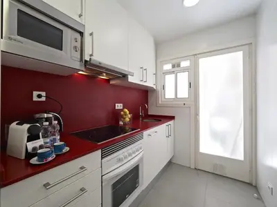 a kitchen with white cabinets and a red wall at Sagrada Penthouse in Barcelona