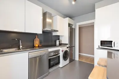 a kitchen with white cabinets and a washer and dryer at Port Forum Apartments by Olala Homes in Sant Adria de Besos