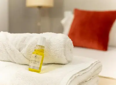 a bottle of essential oil sitting on a pile of towels at GREAT SPACIOUS APARTMENT IN THE GOTHIC QUARTER in Barcelona
