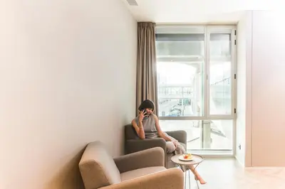 a woman sitting in a chair talking on a cell phone at Sleep&Fly in El Prat de Llobregat