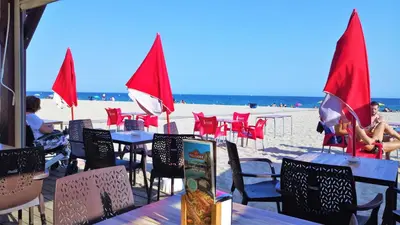 a beach with tables and chairs and red flags at MARISOL SEAVIEW & BEACH - apartment in Masnou