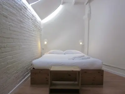 a white bedroom with a bed and a brick wall at Barcelona Mercaders Apartments in Barcelona