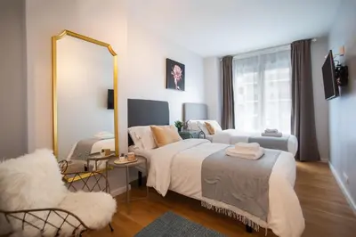 a bedroom with two beds and a mirror and a chair at Tendency Apartments Forum in Sant Adria de Besos