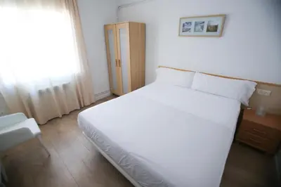 a bedroom with a white bed and a window at Gatell Hotel in Vilanova i la Geltrú