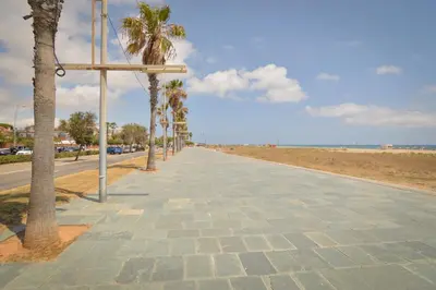 a sidewalk next to the beach with palm trees at VILLA BELLA ESTANÇA in Castelldefels