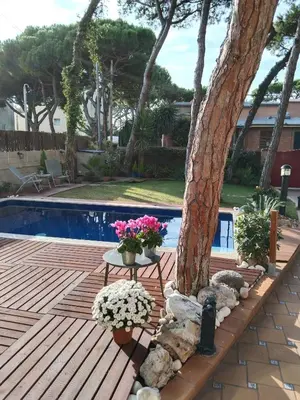 a wooden deck next to a tree next to a pool at VILLA BELLA ESTANÇA in Castelldefels