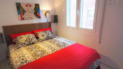 a bedroom with a bed with a red comforter and a window at CATALINA PORT & BEACH -3 dormitorios in Masnou