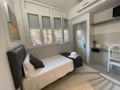 a bedroom with a bed and two windows and a crib at Hostal Lleida in Barcelona