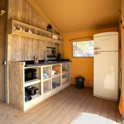 a kitchen with wooden cabinets and a refrigerator at HolaCamp Sitges Garrofer in Sitges