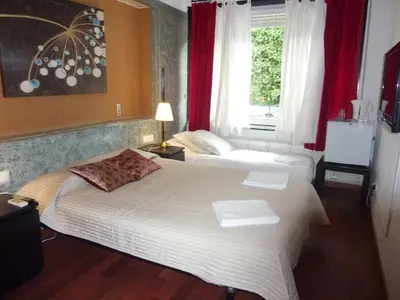 a bedroom with two beds and a window with red curtains at Casa Vilaró Park Guell in Barcelona