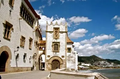 a building with a clock tower next to the water at Apartamento con Licencia en Sitges in Sitges