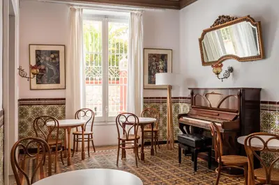 a room with a piano and tables and chairs at Hotel Medium Romantic in Sitges