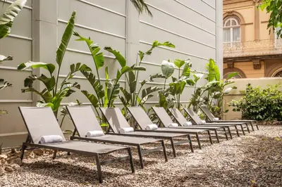 a row of chaise lounge chairs in front of a building at Hotel Medium Romantic in Sitges