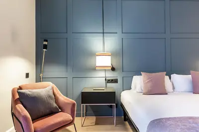 a bedroom with a bed and a chair and a lamp at Weflating City Center in Barcelona