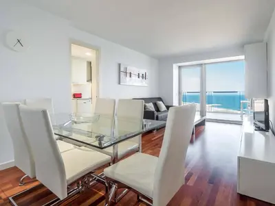 a dining room with a glass table and white chairs at Rent Top Apartments Beach-Diagonal Mar in Barcelona