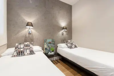 two beds in a room with two lamps on the wall at AinB Eixample-Miro Apartments in Barcelona