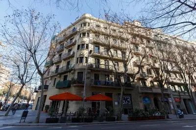 a large building on a city street with orange umbrellas at AinB Eixample-Miro Apartments in Barcelona