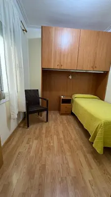 a bedroom with a yellow bed and a chair at Pensión Laforja in Barcelona