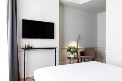a white room with a bed and a tv on a wall at Maldà Singular Hotel in Barcelona