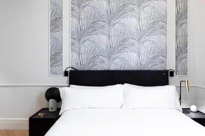 a bedroom with a bed with white sheets and a wallpaper at Maldà Singular Hotel in Barcelona