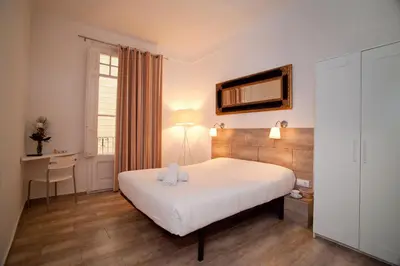 a bedroom with a bed and a desk and a window at Hostal Martinval in Barcelona