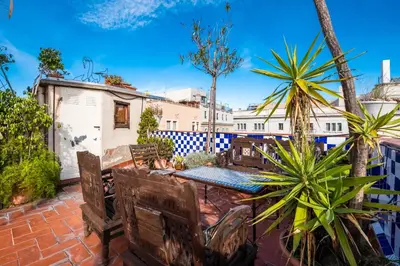 a patio with a table and chairs and palm trees at Apartamentos El Pintor in Barcelona