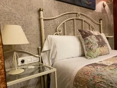 a bedroom with a bed and a glass table with a lamp at Hostal Orleans in Barcelona