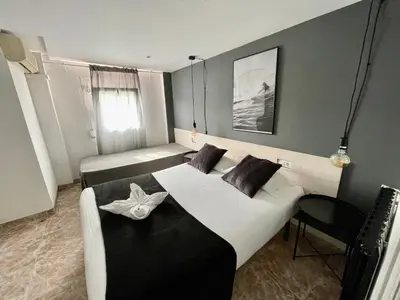 a hotel room with two beds and a chair at Madison Rooms in Sitges