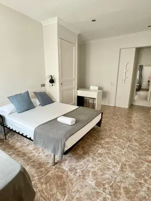 a bedroom with a large bed and a table at Madison Rooms in Sitges