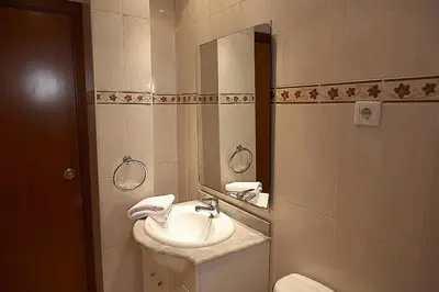 a bathroom with a sink and a mirror and a toilet at Alguera Apartments Sant Andreu in Barcelona