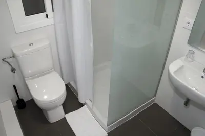 a white bathroom with a toilet and a sink at Hostalin Barcelona Diputacion in Barcelona