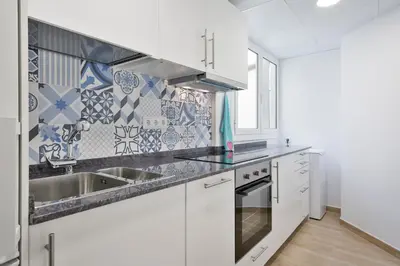 a kitchen with white cabinets and blue and white tiles at Pis Ocata in Masnou