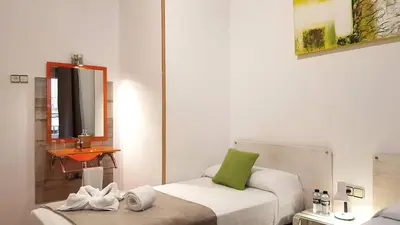 a small room with a bed and a mirror at Hostal la Palmera in Barcelona