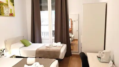 a hotel room with two beds and a mirror at Hostal la Palmera in Barcelona