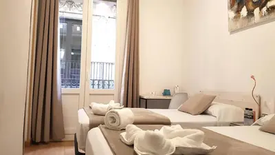 a hotel room with two beds and a window at Hostal la Palmera in Barcelona