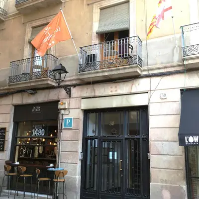a building with tables and chairs and a balcony at Hostal la Palmera in Barcelona