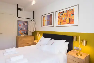 a bedroom with a white bed and some paintings on the wall at Petit Luxe l'Oasi d'Egara in Terrassa