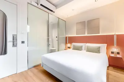 a bedroom with a large white bed and glass walls at LeMar by Aspasios in Barcelona
