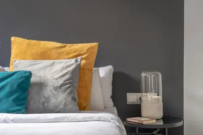 a bed with pillows and a side table with a lamp at TSA La Rosa in Barcelona