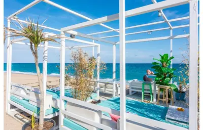 a man sitting at a table on a balcony overlooking the ocean at HomeHolidaysRentals Salvador in Pineda de Mar
