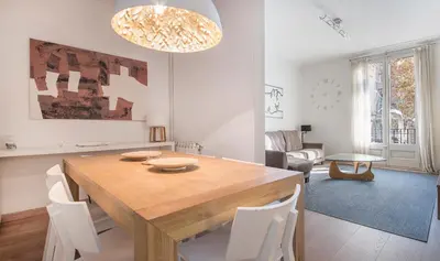 a dining room with a wooden table and white chairs at You Stylish Diagonal Apartments in Barcelona