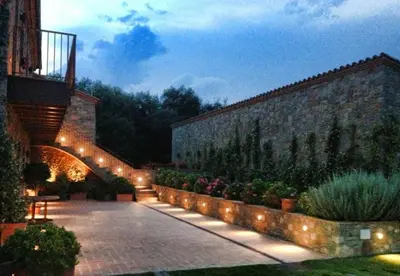 a courtyard with a stone wall and lights at Hotel Rural Can Vila in Sant Esteve de Palautordera