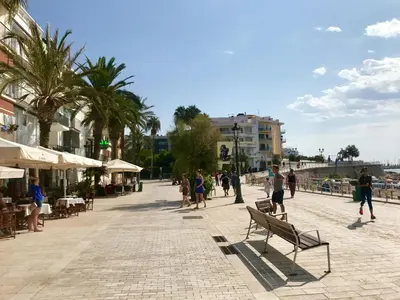 a group of people walking on a street with palm trees at Seaside Apartment in Sitges Steps from Beaches with private Patio in Sitges