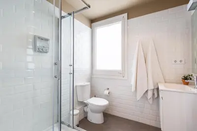 a white bathroom with a toilet and a window at Ola Living Diagonal Apartments in Barcelona
