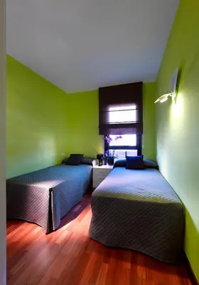 two beds in a room with green walls and wooden floors at Castro Exclusive Residences Sant Pau in Barcelona
